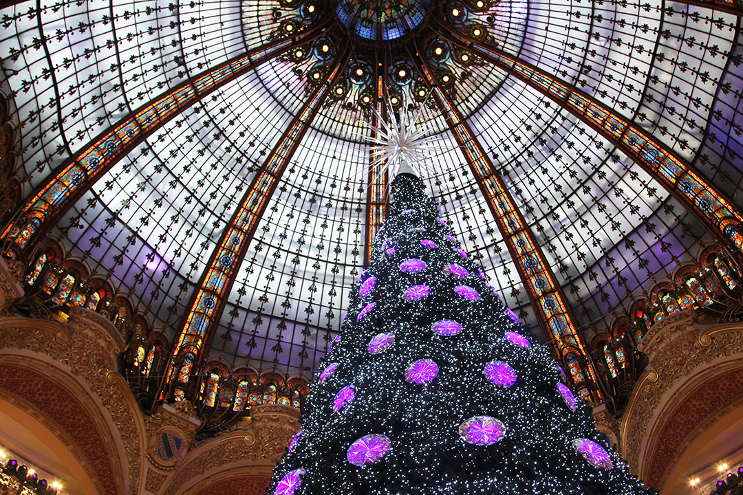 Christmas tree at Galleries Lafayette, Paris with purple baubles and a silver star beneath a glass dome
